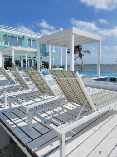 a group of lounge chairs sitting on the beach at Island Magic Villas in Caye Caulker