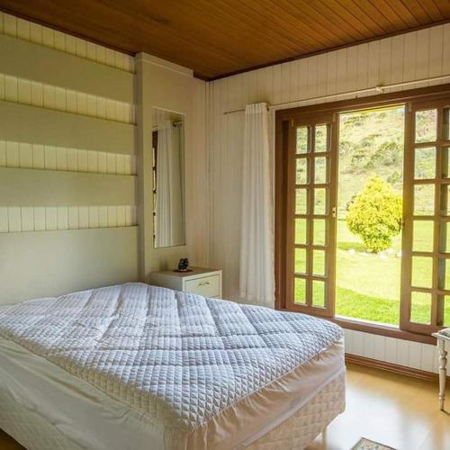 a bedroom with a bed and a large window at Chalés Rota das Cachoeiras in Urupema