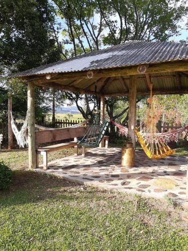 a wooden gazebo with a hammock and a bench at Chalés Rota das Cachoeiras in Urupema