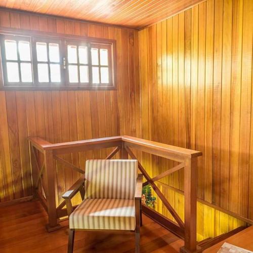 a wooden room with a chair and a window at Chalés Rota das Cachoeiras in Urupema