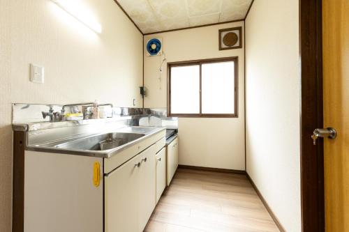 a small kitchen with a sink and a window at Guest House 来夢 in Otaru