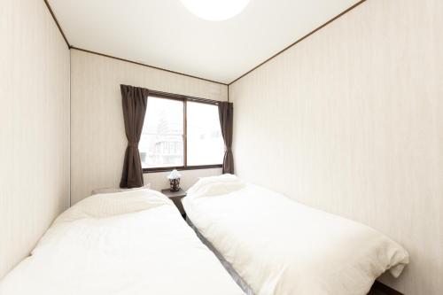 two beds in a room with a window at Guest House 来夢 in Otaru