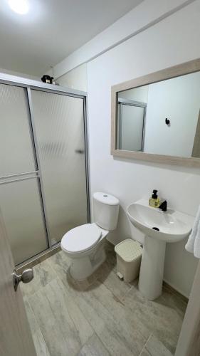 a bathroom with a toilet and a sink and a mirror at Hospedaje Los Termales in Villamaría
