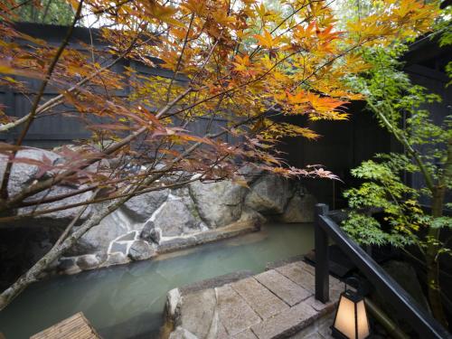 a tree with orange leaves next to a body of water at Hikyou Shirakawagensen Sansou Takefue in Minamioguni