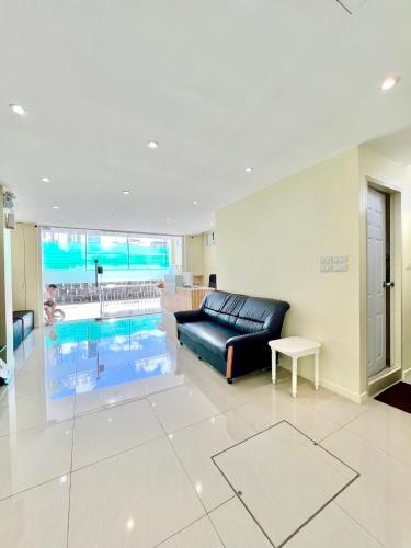 a living room with a black leather couch and a pool at ABC HA Hotel Bangkok in Bangkok