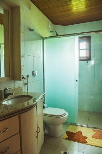 a bathroom with a toilet and a sink and a shower at Chalés Rota das Cachoeiras in Urupema