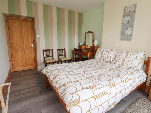 a bedroom with a bed and two chairs in it at Budle Bay Cottage in Bamburgh