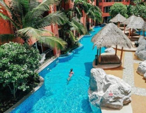 une piscine dans un complexe hôtelier avec une personne qui nage dedans dans l'établissement Seven sea jomtien by new, à Jomtien Beach