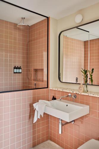 a pink tiled bathroom with a sink and a mirror at Turing Locke Cambridge in Cambridge
