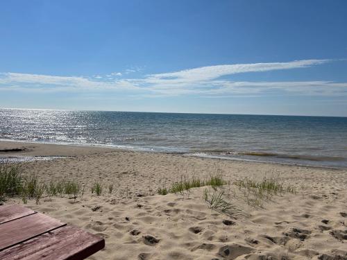 a beach with a wooden bench and the ocean at The Amazing Escape in Manistee