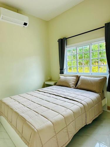 a bedroom with a large bed and a window at หลัง 2 เฌอเฌอ การ์เด้น เฮาส์ ที่พักคำชะโนด in Ban Nong Sawang