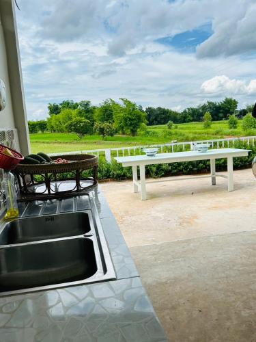 a kitchen with a sink and a bench on a patio at หลัง 2 เฌอเฌอ การ์เด้น เฮาส์ ที่พักคำชะโนด in Ban Nong Sawang
