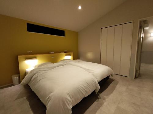a bedroom with a large bed with white sheets at Refwind in Kyonan