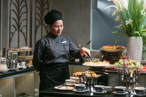 a woman in a kitchen preparing food at MAY DE VILLE Crown Hotel in Hanoi