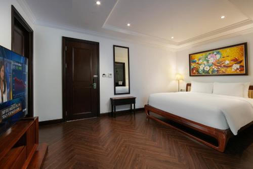 a bedroom with a large white bed and a tv at MAY DE VILLE Crown Hotel in Hanoi