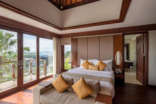 a bedroom with a large bed and large windows at tanadewa Villas Nusa Dua Bali by Cross Collection in Nusa Dua