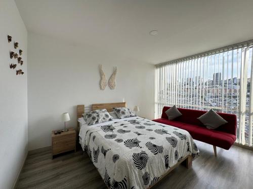 a bedroom with a bed and a red couch at Barcelona in Manizales