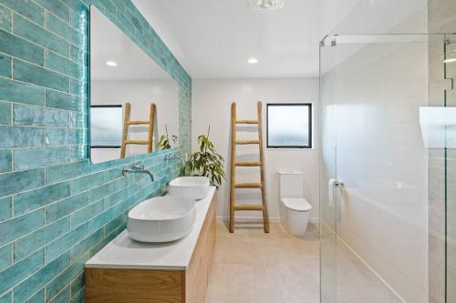 a bathroom with two sinks and a glass shower at Aqua Vista Seaside Retreat in Papamoa