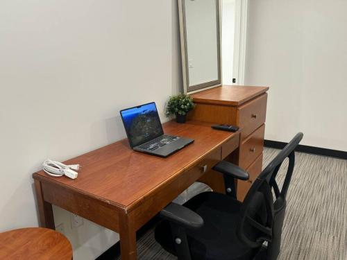 a wooden desk with a laptop computer on it at Cozy Motel Studio with kitchenette - 7 in Edmonton