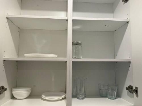 a white shelf with bowls and glasses on it at Cozy Motel Studio with kitchenette - 7 in Edmonton