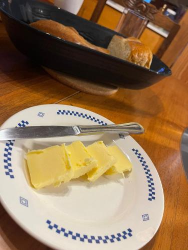a piece of cheese on a plate with a knife and bread at Les Iris in Fontenay-près-Vézelay