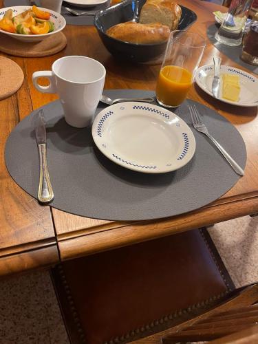 - une table avec une assiette et une tasse de jus d'orange dans l'établissement Les Iris, à Fontenay-près-Vézelay
