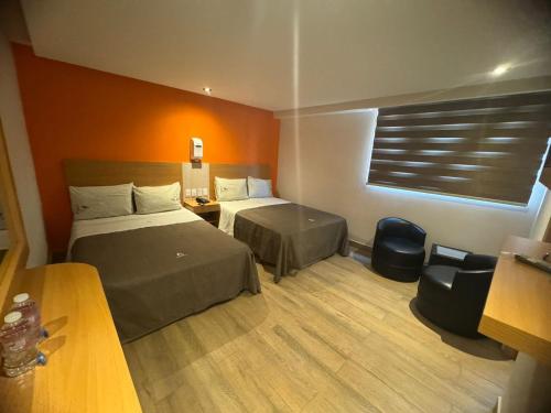 a hotel room with two beds and a desk at Hotel Moctezuma La Villa in Mexico City
