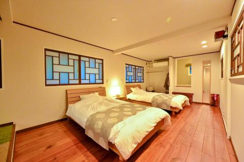 a bedroom with two beds and two windows at Ikkoten in Yufuin