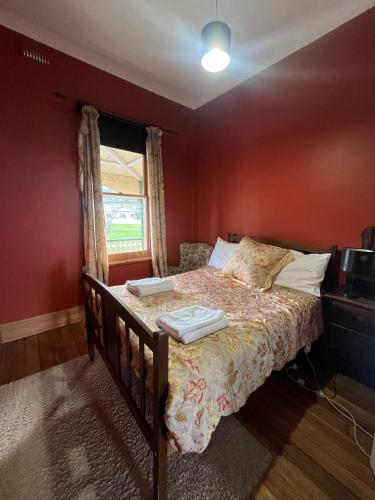 a bedroom with a bed with red walls and a window at St Marys Hotel in Saint Marys