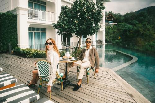 a man and a woman sitting at a table by a pool at Marina Gallery Resort-KACHA-Kalim Bay - SHA Plus in Patong Beach