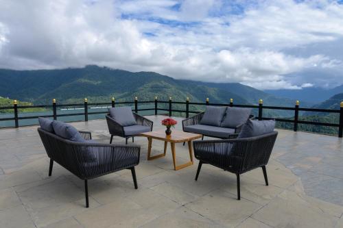 a patio with chairs and a table and mountains at Willing Resort, Trongsa in Kagha