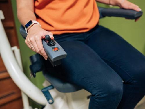 a woman is sitting in a chair with a remote control at Holiday home for group with sauna and pool in Havelte