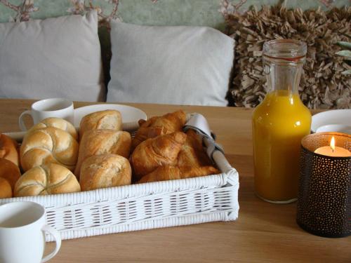 a table with a basket of bread and a bottle of orange juice at Rural holiday home with outdoor pool & sauna in Zuidzande