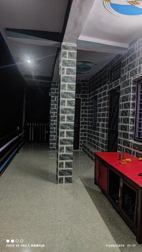 Una habitación con paredes de ladrillo y una mesa roja. en Krishna homestay, en Uttarkāshi