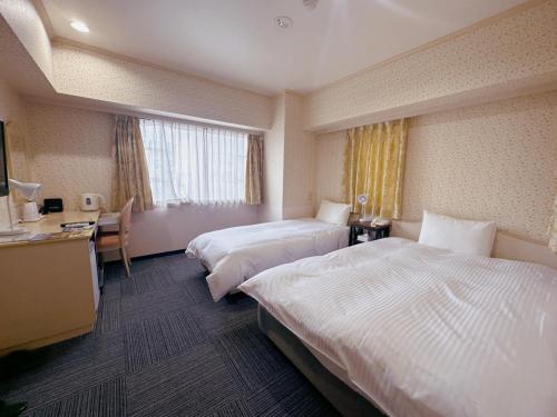 a hotel room with two beds and a desk at Nissei Hotel Fukuoka in Fukuoka