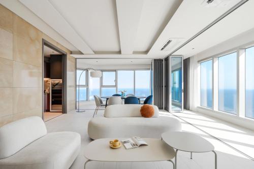 a living room with white furniture and large windows at Le Collective Haeundae Paragraf in Busan