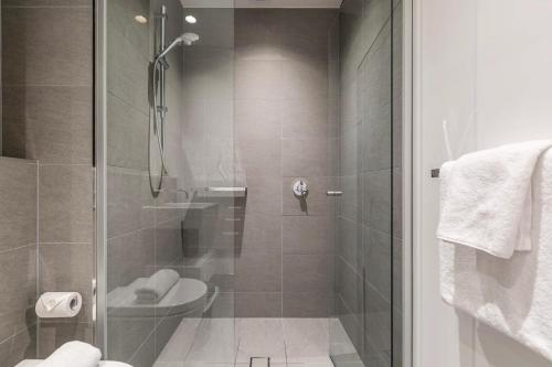 a bathroom with a toilet and a glass shower at Vibrant & Lively Condo with Stunning City Views in Melbourne