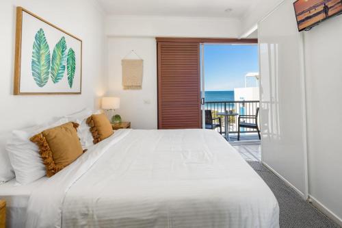 a bedroom with a large white bed and a balcony at Top Floor Unit With Private Rooftop Terrace in Caloundra