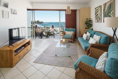a living room with blue furniture and a view of the ocean at Top Floor Unit With Private Rooftop Terrace in Caloundra
