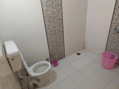 a bathroom with a toilet and a pink trash can at HOTEL TOURIST REST HOUSE Agra in Agra