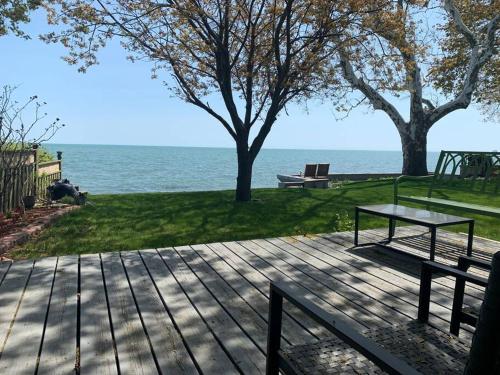 a picnic table and a bench on a deck near the water at "Hook, Line,& Sinker"-At the edge of Erie 7 plus 1 in Kingsville