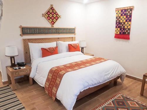 a bedroom with a large bed with white sheets and orange pillows at SERENA ALTIT FORT RESIDENCE in Hunza