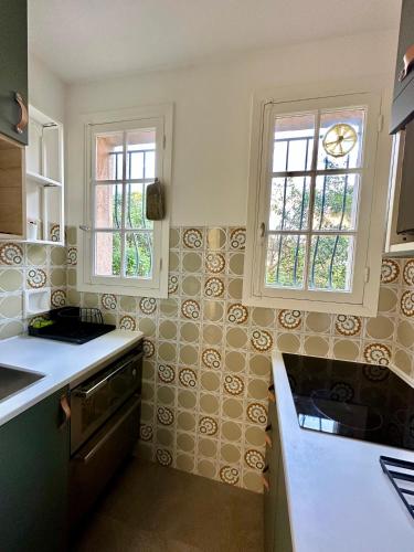 une cuisine avec un évier et deux fenêtres dans l'établissement Beau studio mer et plages, à Cagnes-sur-Mer