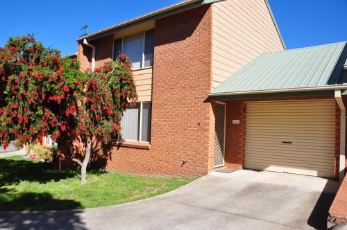 a brick house with a garage and a tree at The Bottlebrush in Tumut