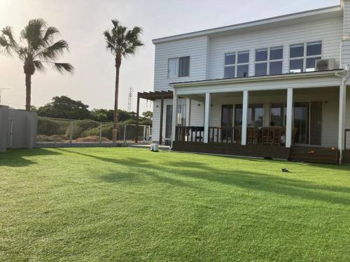 a house with a large yard with palm trees at 海まで徒歩5分-BBQ バレルサウナ ジャグジー ペットOKの貸切villa in Ichinomiya