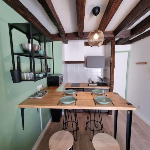 - une cuisine avec une table en bois et des tabourets dans l'établissement Au perchoir duplex dans le centre historique, à Orléans