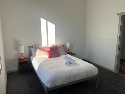 a bed with pink and white pillows and a window at Pickaxe and Pillow in Ballarat