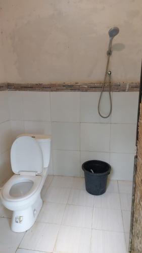 a bathroom with a toilet and a black bucket at Arnata Guest House & Pasraman Yoga Lokanata in Bangli