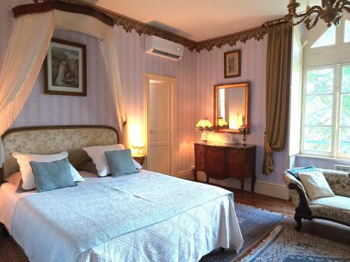 a bedroom with a bed and a chair and a window at Château de la Vernède, la Grande Vernède in Saint-Rémy-de-Chargnat