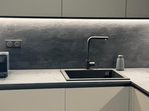 - une cuisine avec un évier et un mur noir dans l'établissement Appartement rétro dans le centre, à Antibes